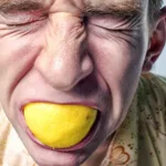 foto di persona che soffre con una buccia di limone in bocca